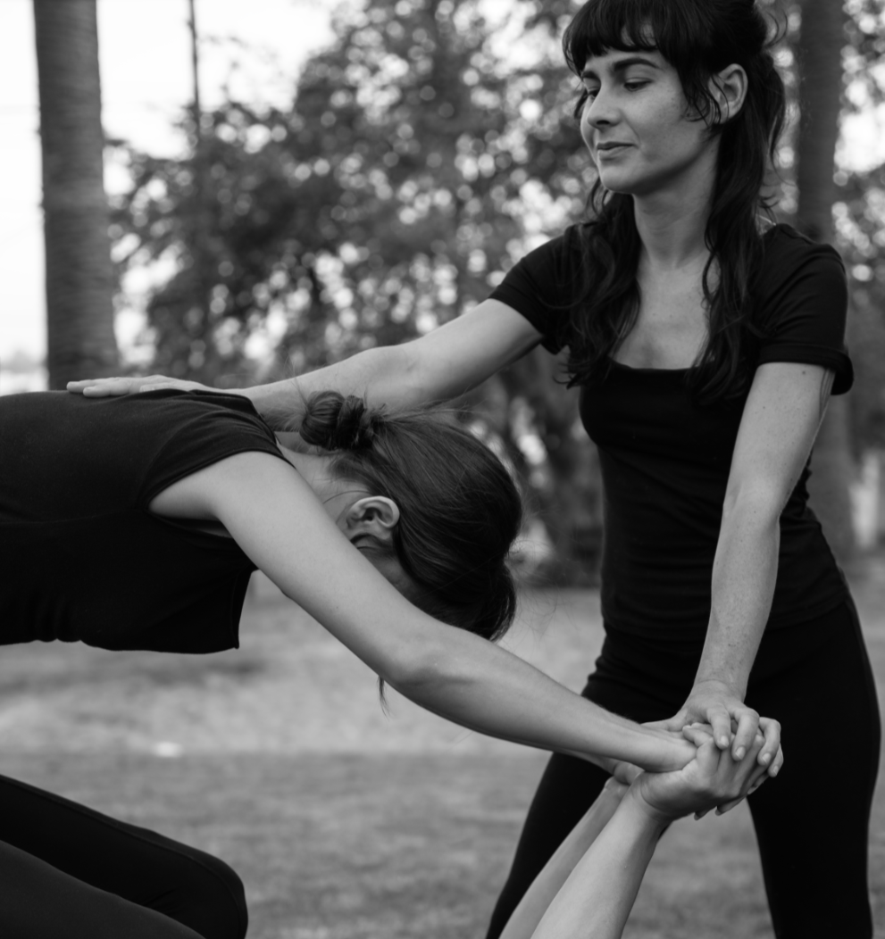Holly Saitta guiding a partner through a supported yoga stretch