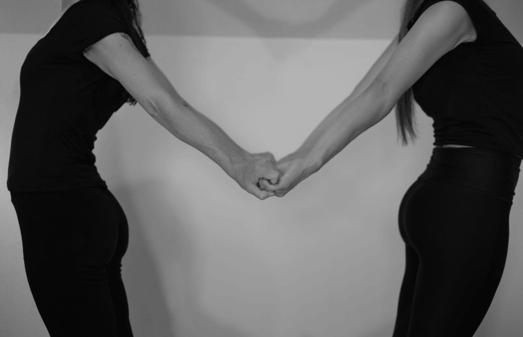Two partner yoga practitioners holding hands