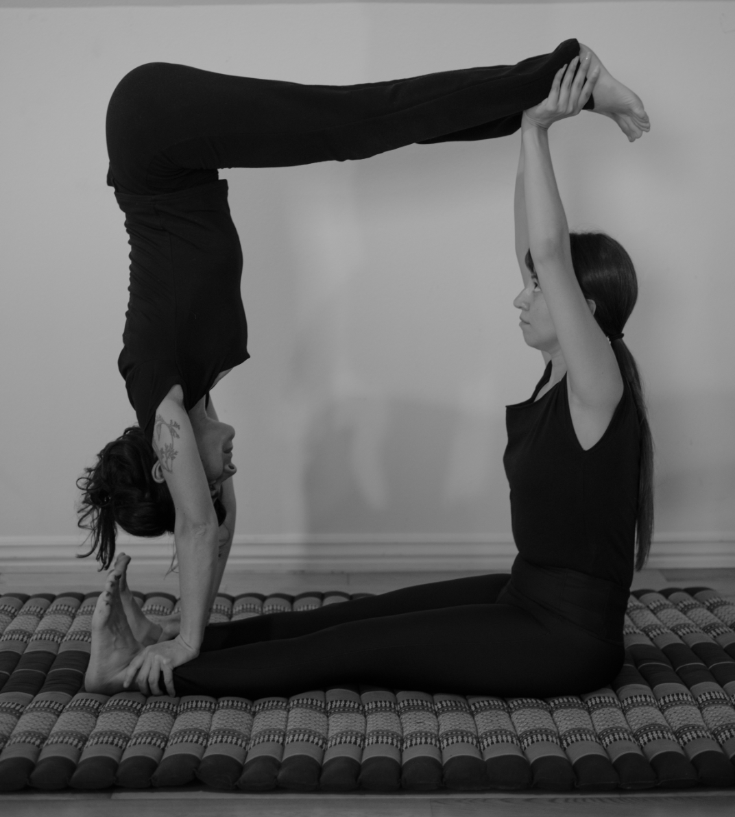 Two people practicing a supported partner yoga inversion